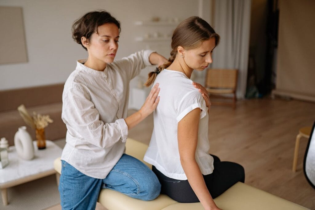 A female therapist provides a back massage therapy session to a client in a serene spa setting.